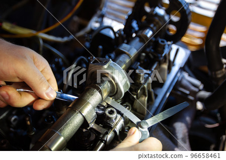 Mercedes diesel engine repair. Hands with a mechanic repairing Mercedes parts. Valve clearance adjustment. 96658461