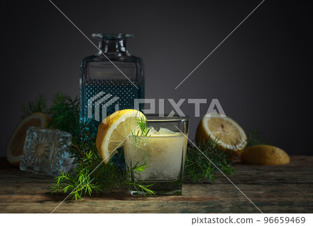 Cocktail with blue gin, tonic, and lemon on an old wooden table. Cocktail with blue gin, tonic, and lemon on an old wooden table. 96659469