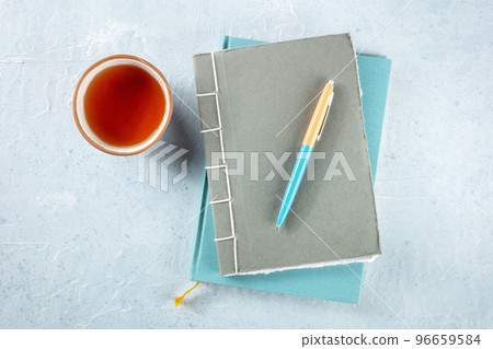 Diary. Journals with a pen and a cup of tea, overhead flat lay shot on a desk Diary. Journals with a pen and a cup of tea, overhead flat lay shot on a desk 96659584