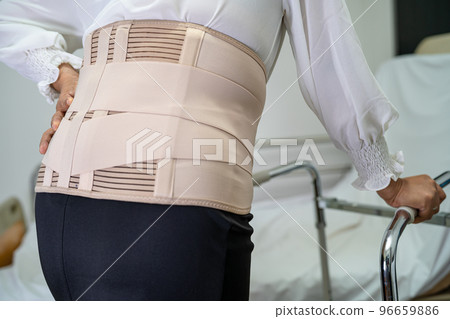 Asian lady patient wearing back pain support belt for orthopedic lumbar with walker. 96659886