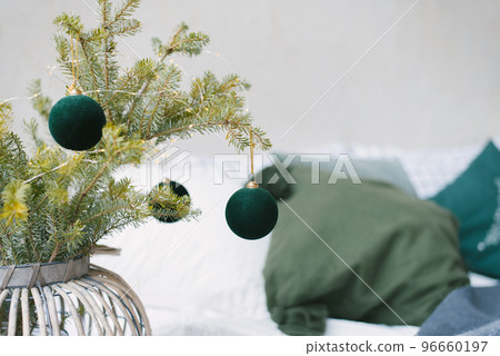 Emerald Christmas balls on fir branches with lights that stand in a wicker vase Emerald Christmas balls on fir branches with lights that stand in a wicker vase 96660197
