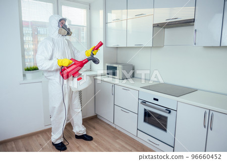 white worker spraying pesticide on induction hob white worker spraying pesticide on induction hob 96660452