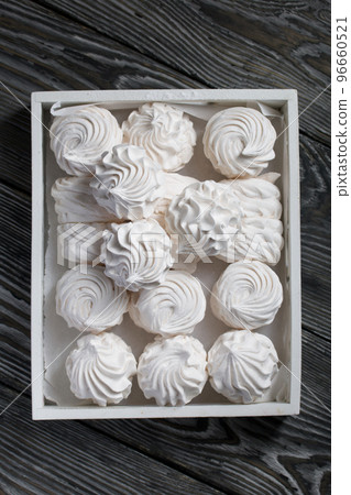 Homemade zephyr. White tray with marshmallows. Stands on black pine boards. 96660521