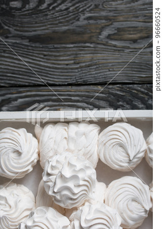 Homemade zephyr. White tray with marshmallows. Stands on black pine boards. Homemade zephyr. White tray with marshmallows. Stands on black pine boards. 96660524