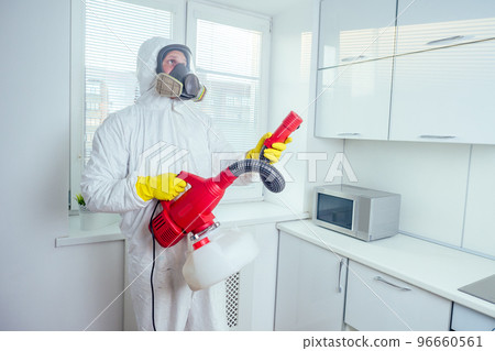 white worker spraying pesticide on induction hob 96660561