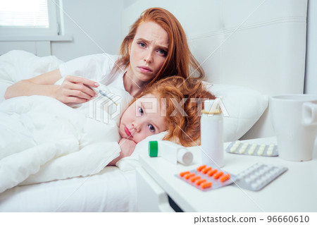 redhaired ginger woman and her ill child taking the temperature at morning redhaired ginger woman and her ill child taking the temperature at morning 96660610
