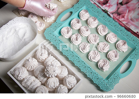 Homemade zephyr. White tray with marshmallows. Stands on black pine boards. 96660680