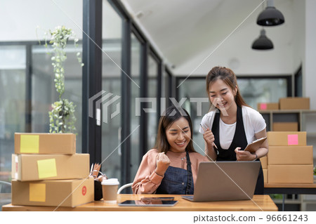 Happy two asian women entrepreneur, Smile for sales success after checking order from online shopping store in a smartphone at home office, Concept of merchant business online and eCommerce 96661243