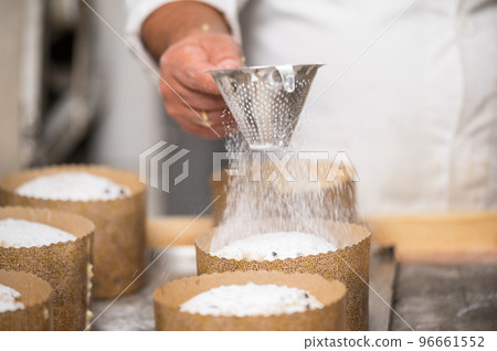 Pastry chef Topping Traditional Italian panettones with powdered sugar. 96661552