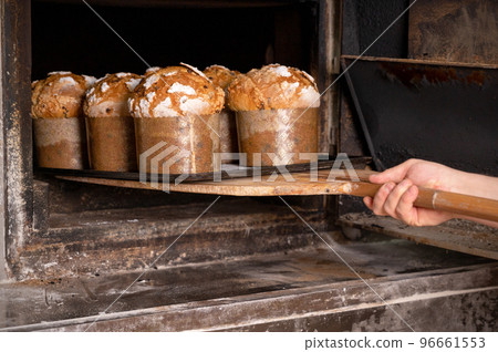 Baker taking out baked panettone from oven 96661553