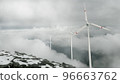 Wind turbines on a mountain pass, renewable energy. Clouds are floating, a hazy haze. Snow. The concept of renewable energy sources. 96663762