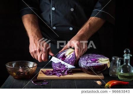 The chef is cutting red cabbage with a knife. Cooking vegetable salad in the restaurant kitchen. Vegetable diet idea 96663843