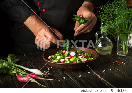 Cooking a salad of fresh vegetables by the hands of a chef in the kitchen. Vegetarian cuisine. Recipe menu for hotel Cooking a salad of fresh vegetables by the hands of a chef in the kitchen. Vegetarian cuisine. Recipe menu for hotel 96663884