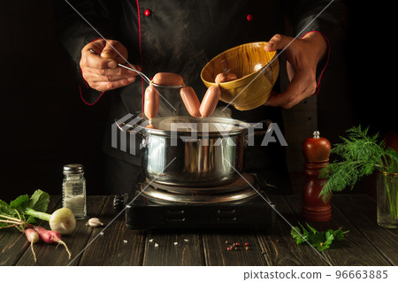 For dinner need to cook delicious meat sausages in a saucepan. Chef in the kitchen at work. Menu idea for a hotel or restaurant. For dinner need to cook delicious meat sausages in a saucepan. Chef in the kitchen at work. Menu idea for a hotel or restaurant. 96663885