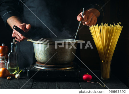 Chef prepares Italian pasta on the background of vegetables. Close-up of chef is hand during cooking in a restaurant kitchen 96663892