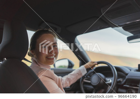 Rear view of young woman driving her electric car. Rear view of young woman driving her electric car. 96664190