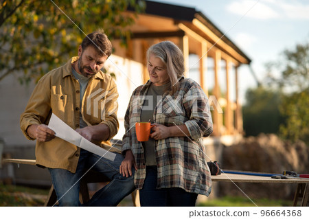 Mature couple having coffee break when working together on construction site of their new house. Mature couple having coffee break when working together on construction site of their new house. 96664368