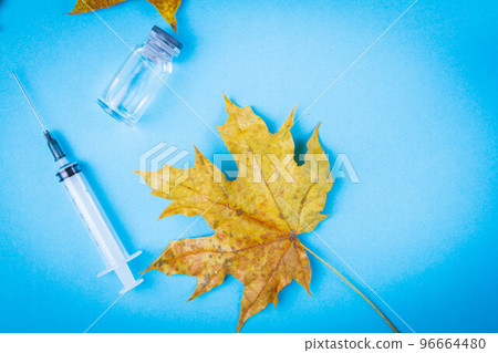 Maple leaf and antidote with syringe on blue background. Treatment of diseases in autumn. 96664480