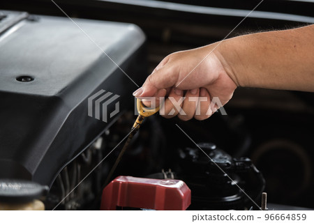 Man hand pulling oil gauge stick up for checking level of motor oil lubricant in the engine, car maintenance service concept. 96664859
