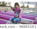 Cute caucasian boy posing in a pink stylish printed t-shirt among pink iron pipes on an industrial background. Fashion style photoshoot 96665261