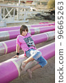 Cute caucasian boy posing in a pink stylish printed t-shirt among pink iron pipes on an industrial background. Fashion style photoshoot 96665263
