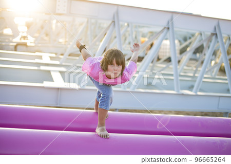 Cute caucasian boy posing in a pink stylish printed t-shirt among pink iron pipes on an industrial background. Fashion style photoshoot 96665264