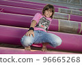 Cute caucasian boy posing in a pink stylish printed t-shirt among pink iron pipes on an industrial background. Fashion style photoshoot 96665268
