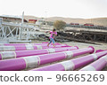 Cute caucasian boy posing in a pink stylish printed t-shirt among pink iron pipes on an industrial background. Fashion style photoshoot 96665269