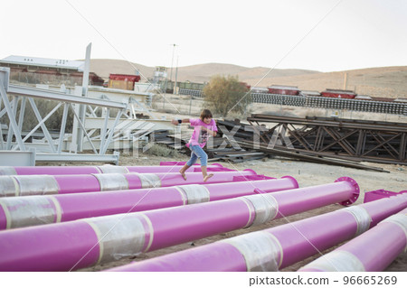 Cute caucasian boy posing in a pink stylish printed t-shirt among pink iron pipes on an industrial background. Fashion style photoshoot Cute caucasian boy posing in a pink stylish printed t-shirt among pink iron pipes on an industrial background. Fashion style photoshoot 96665269