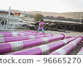 Cute caucasian boy posing in a pink stylish printed t-shirt among pink iron pipes on an industrial background. Fashion style photoshoot 96665270