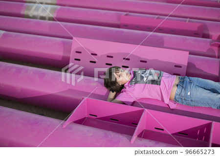 Cute caucasian boy posing in a pink stylish printed t-shirt among pink iron pipes on an industrial background. Fashion style photoshoot 96665273