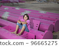 Cute caucasian boy posing in a pink stylish printed t-shirt among pink iron pipes on an industrial background. Fashion style photoshoot 96665275