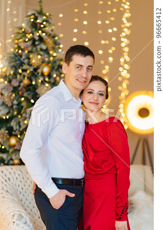 a happy and elegant couple in a room with a christmas tree and a garland a happy and elegant couple in a room with a christmas tree and a garland 96665412