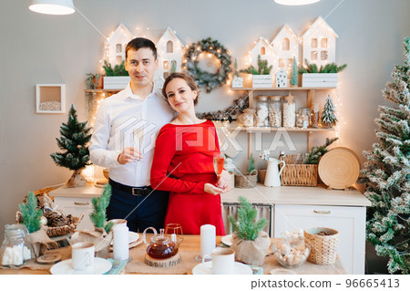a happy and elegant couple with champagne in the Christmas kitchen. a happy and elegant couple with champagne in the Christmas kitchen. 96665413