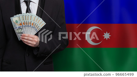 Man showing 100 us dollar bills against flag of Azerbaijan background 96665499