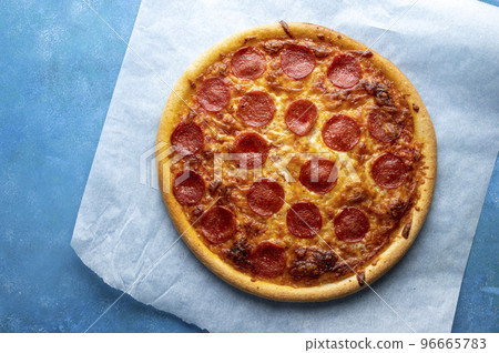 Pepperoni pizza on blue background, one pizza, top view Pepperoni pizza on blue background, one pizza, top view 96665783