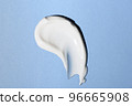 Liquid white cream smear isolated on blue background. Beauty cosmetic smudge such as hair conditioner, creamy lotion, facial retinol serum, mask balm, cleanser, shower gel or shampoo top view 96665908