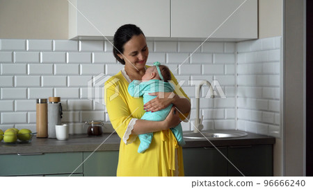 Young happy mother embracing her cute baby in the kitchen. Motherhood and family concept 96666240