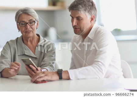 two businessmen at the table looking at the phone 96666274