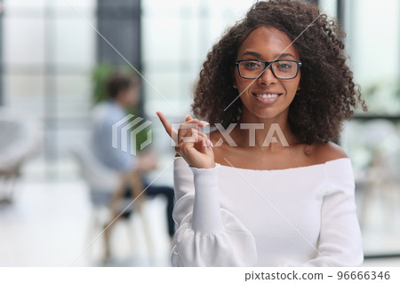 Portrait of african american young business woman showing finger gesture to the side Portrait of african american young business woman showing finger gesture to the side 96666346