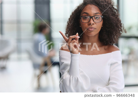 Portrait of african american young business woman showing finger gesture to the side Portrait of african american young business woman showing finger gesture to the side 96666348