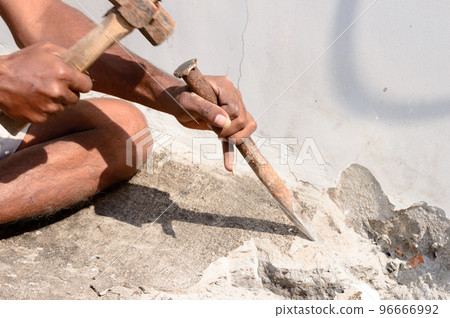 Close up Part of a construction labor working with hammer and Chisel in a construction site. Close up Part of a construction labor working with hammer and Chisel in a construction site. 96666992