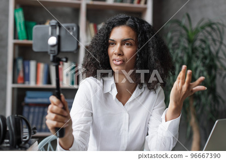 Attractive young multinational woman in white shirt taking selfie on her smart phone using stick. Attractive young multinational woman in white shirt taking selfie on her smart phone using stick. 96667390
