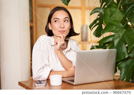 Confident young stylish woman with laptop, sitting in cafe and working, freelancer in co-working space with cup of coffee Confident young stylish woman with laptop, sitting in cafe and working, freelancer in co-working space with cup of coffee 96667870