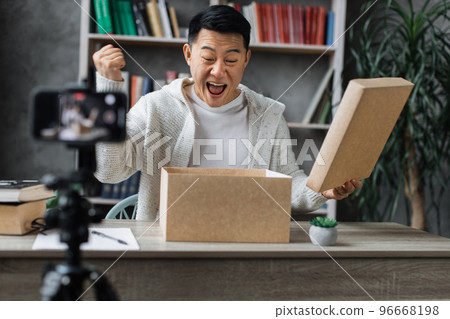 Happy asian male blogger unpacking gift boxes presents from companies and doing live streaming. Happy asian male blogger unpacking gift boxes presents from companies and doing live streaming. 96668198