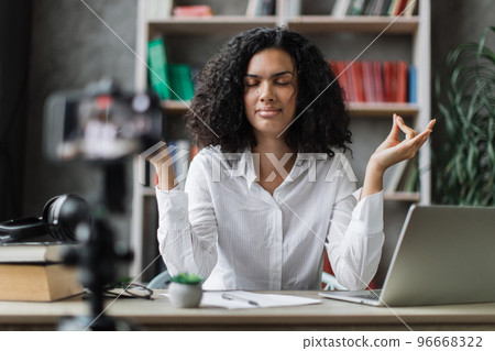 Woman freelancer recording video blog how to relieving stress by meditation at workplace Woman freelancer recording video blog how to relieving stress by meditation at workplace 96668322