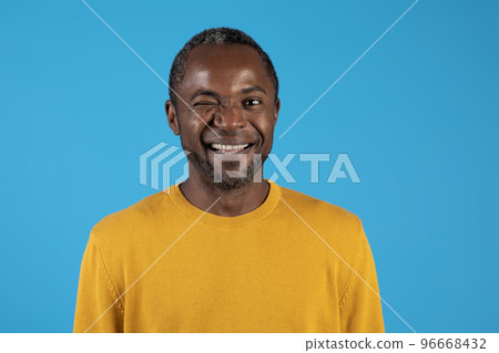 Headshot of handsome black man winking on blue Headshot of handsome black man winking on blue 96668432