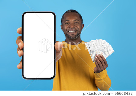 Cheerful rich black man showing smartphone blank screen and cash 96668482