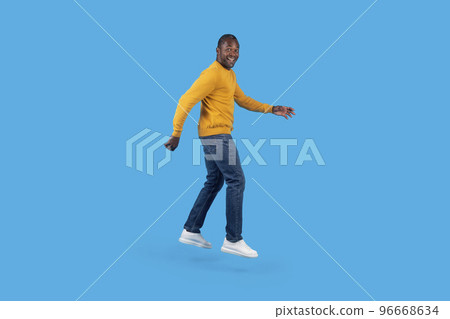 Emotional african american mature man jumping up on blue Emotional african american mature man jumping up on blue 96668634
