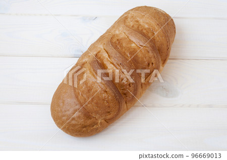 Bun of wheat bread on white wooden table. 96669013